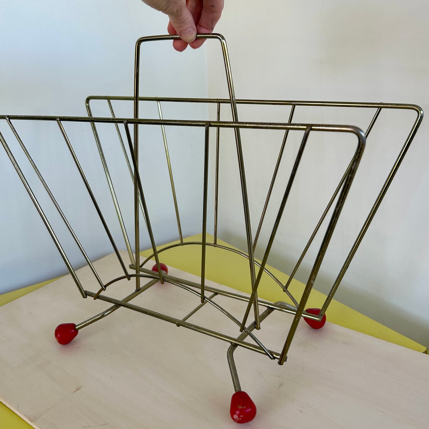 Metal 1950s magazine rack with red wooden feet
